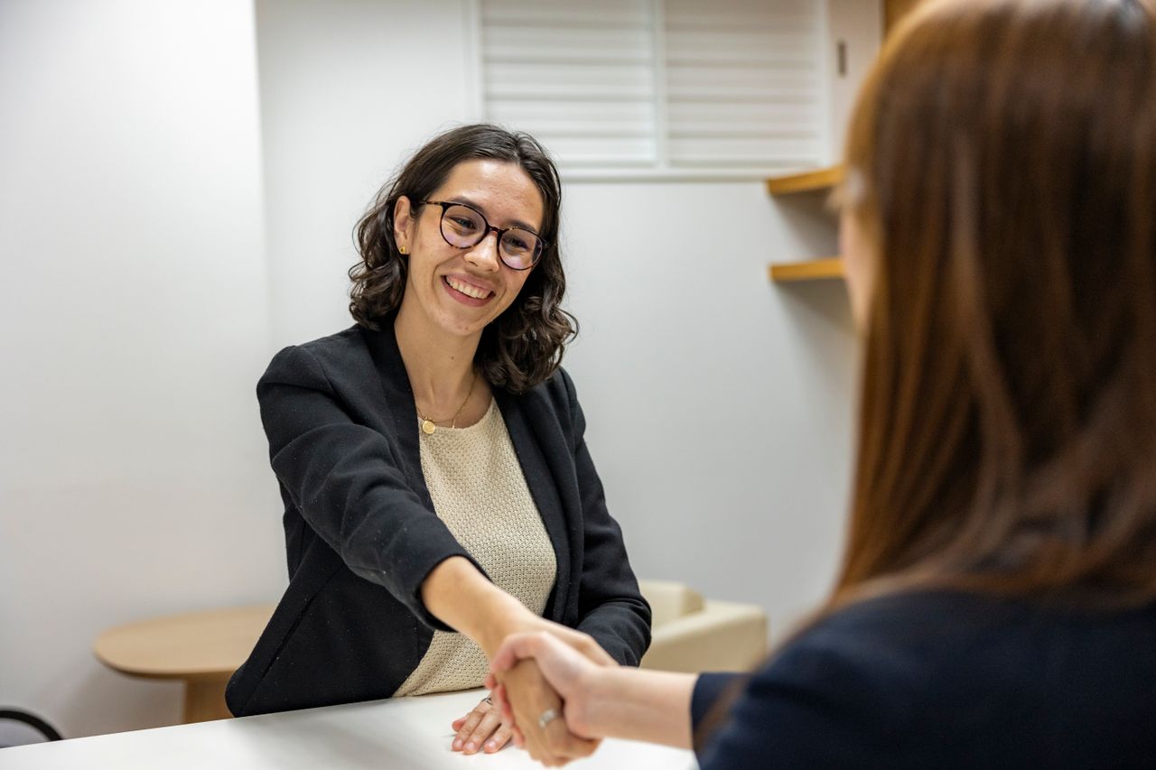 portfolio-04 Businesswomen shaking hands in an office, representing a successful job interview or partnership.